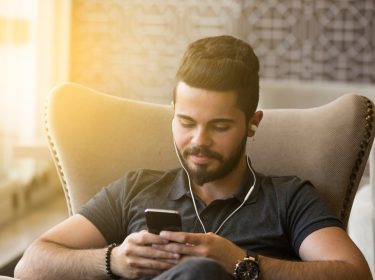 Junger Mann betrachtet entspannt Videos auf einem Smartphone