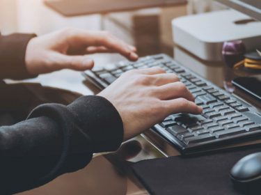 Junger Mann tippt am Computer.