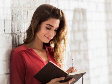 Eine Frau notiert etwas in einem Notizbuch