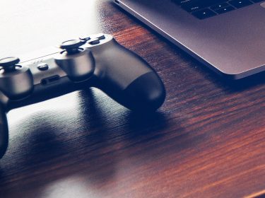 Ein PlayStation 4-Controller neben einem Laptop