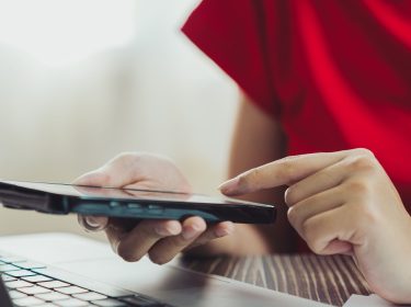 Frau tippt mit ihrem Finger auf ein Smartphone.
