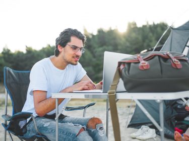 Mann beim Camping hilft einem Freund mit iPhone