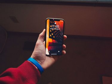 Mann hält iPhone X vor sein Gesicht, um via Face ID zu entsperren.