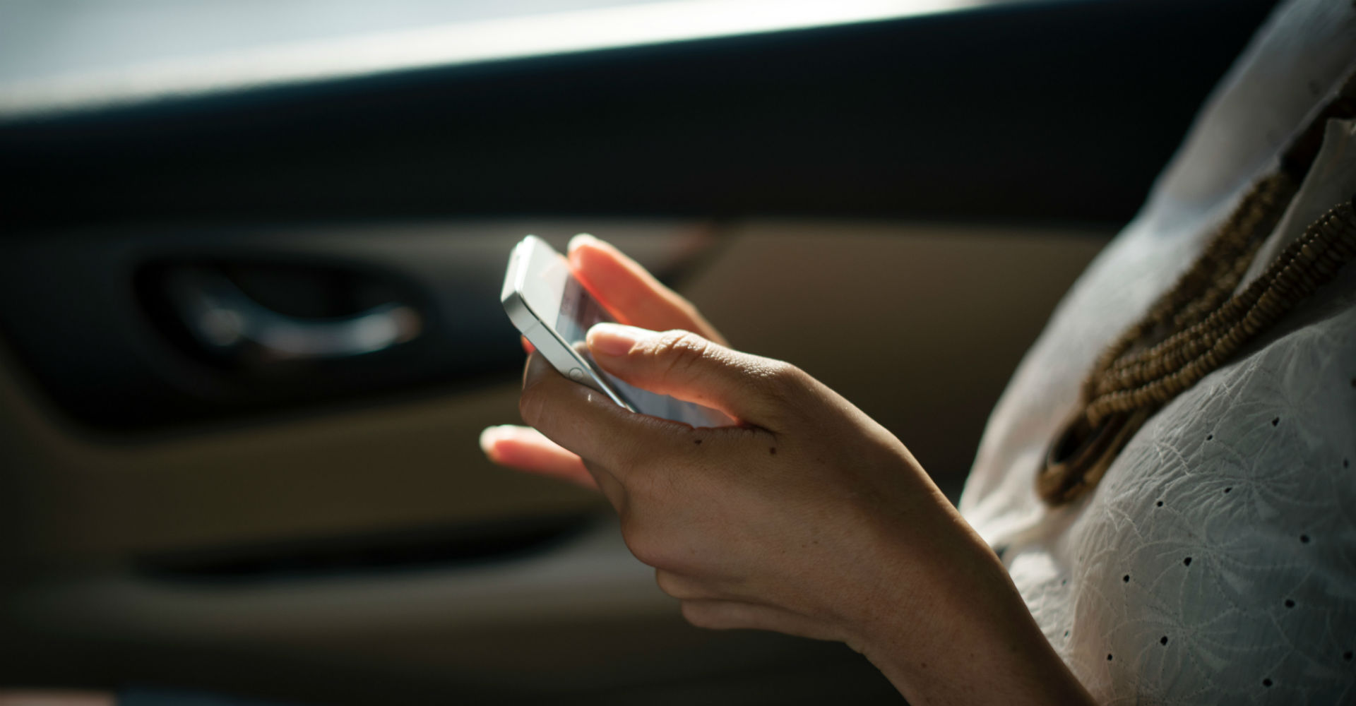 Junge Frau nutzt Smartphone im Auto.