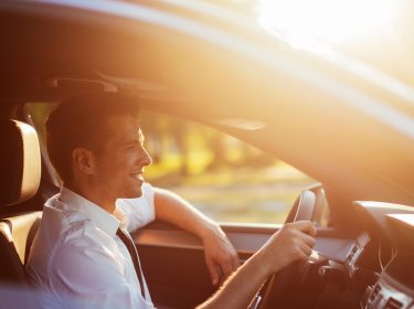 Junger Mann beim Fahren unterhält sich mit Amazon Alexa