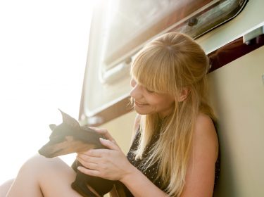 Eine junge Frau mit ihrem Wohnwagen und einem Hund