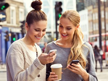 Freundinnen nutzen den Facebook Messenger auf ihren Smartphones.