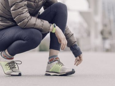 Frau nutzt Fitness-Tracker beim Laufen