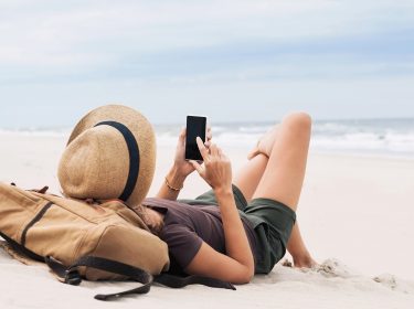 Frau mit Smartphone am Strand