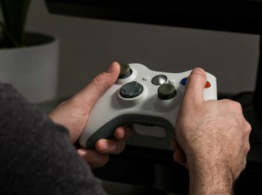 Junger Mann spielt ein Multiplayer-Game mit dem Xbox-Controller.