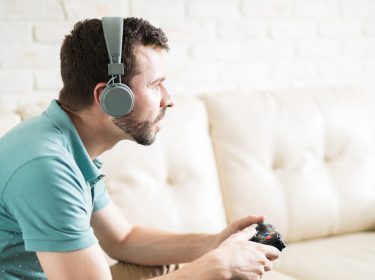 Junger Mann spielt Xbox mit Bluetooth-Kopfhörern