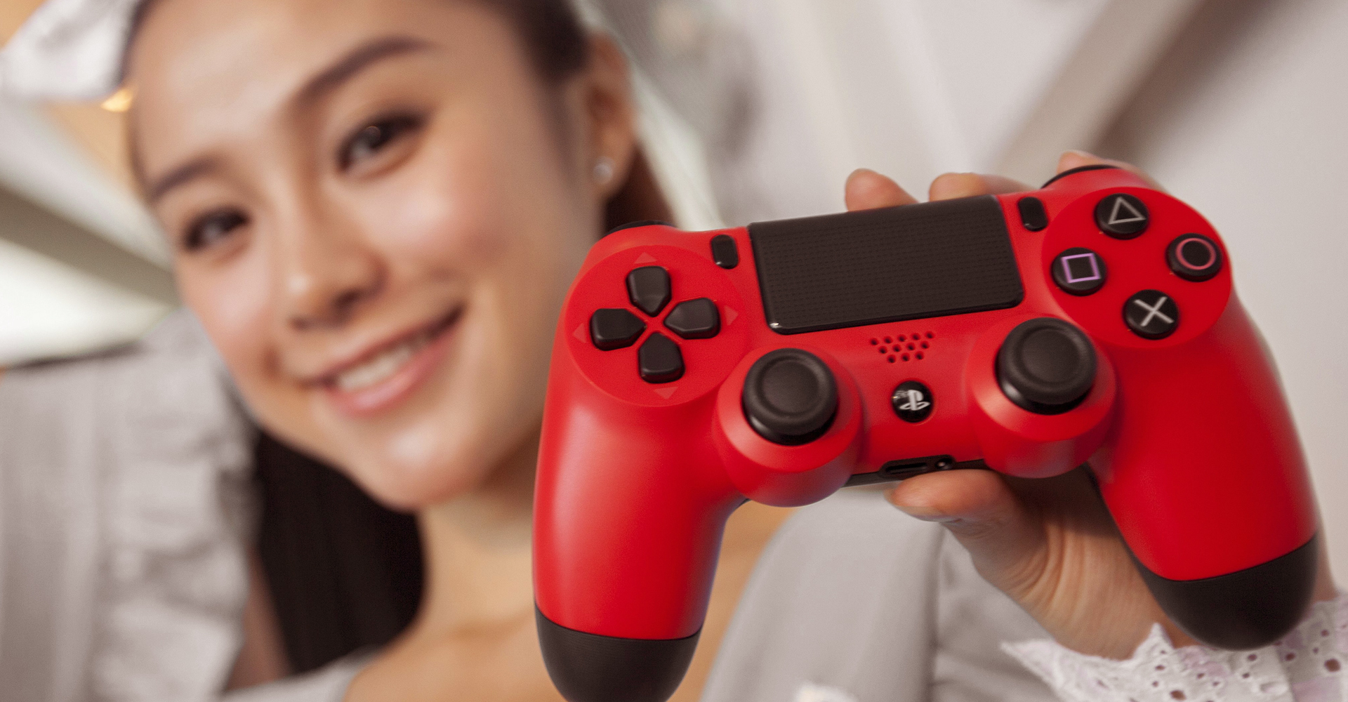 Frau hält einen roten PS4-Controller in die Höhe.