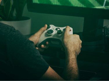 Mann spielt Xbox-Games mit Controller.