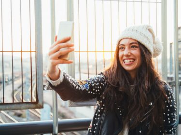 Junge Frau schießt ein Selfie mit ihrem Smartphone.
