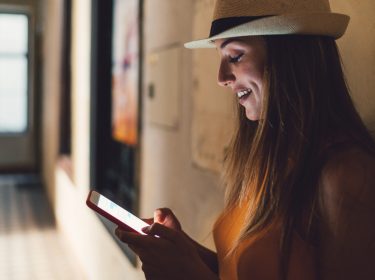 Eine junge Frau findet ihren Weg im Gebäude auf dem Smartphone