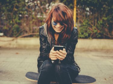 Junge Frau verwendet Twitter am Smartphone.