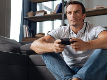 Junger Mann spielt God of War auf Konsole