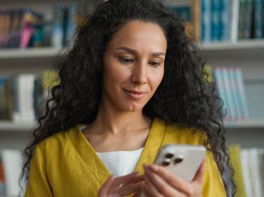 Junge Frau schaut sich etwas auf ihrem iPhone Pro an.