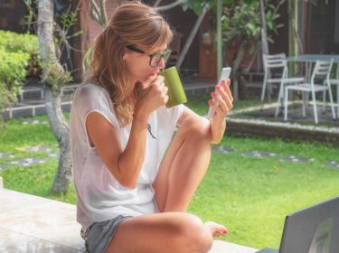 Junge Frau steuert ihren Rasenmäher via App