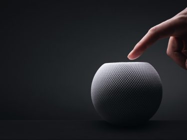 Ein Finger berührt einen HomePod mini
