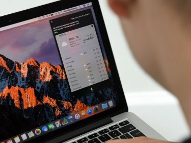 Junger Mann sitzt vor Mac-Computer.