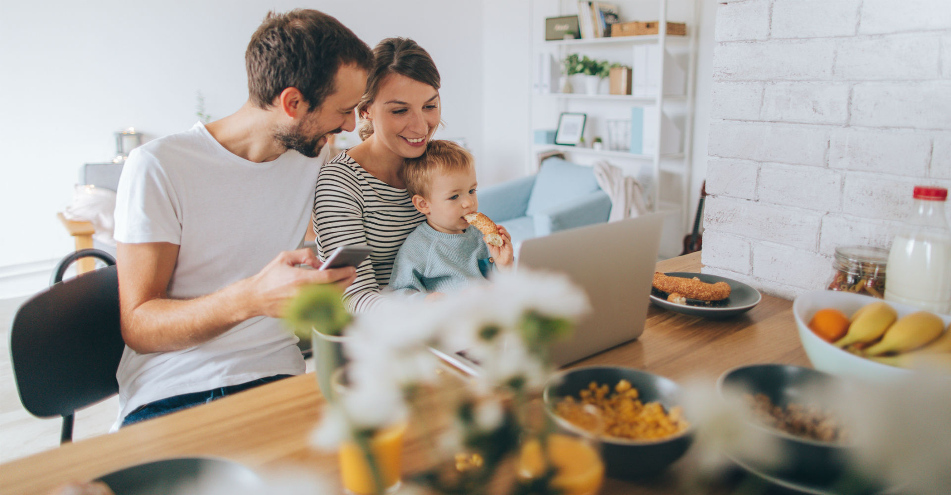 Junge Familie sitzt vor dem Laptop.