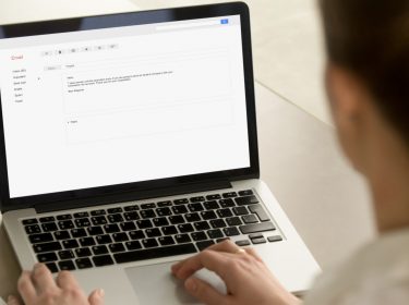 Junge Frau nutzt Gmail auf ihrem Laptop