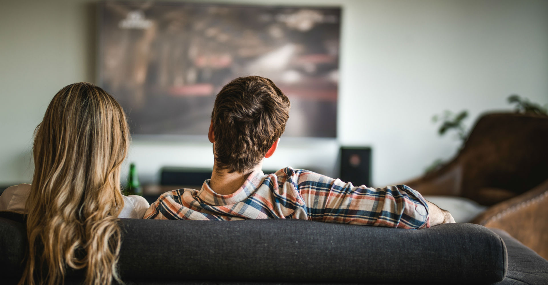 Zwei Menschen sitzen vor dem Fernseher.