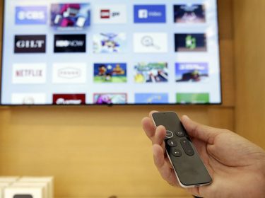 Eine Hand hält die Apple TV Remote.