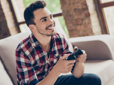 Junger Mann zockt Spider-Man über die Konsole.