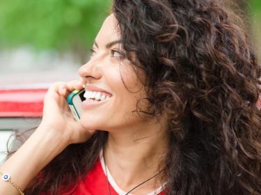 Junge brünette Frau telefoniert mit ihrem Smartphone