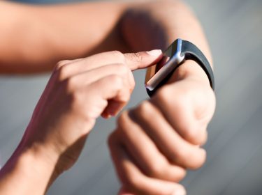 Frau tippt auf das Display ihrer Smartwatch.