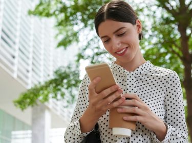 Frau lädt Dateien über ihr Smartphone in die Cloud hoch.