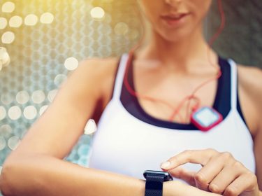 Frau nutzt während des Lauftrainings ihre Smartwatch.