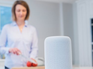 Eine Frau steht in der Küche und telefoniert über ihren HomePod