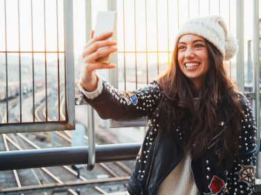 Junge Frau knipst Selfie über einer Eisenbahnbrücke