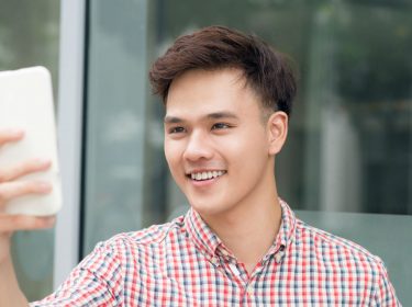 Junger Mann spielt ein AR-Spiel im Facebook Messenger am Smartphone.