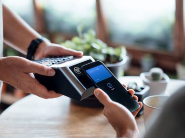 Eine Person bezahlt mobil mit dem Android-Handy.
