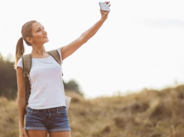 Eine junge Frau macht ein Selfie für ihr neues Facebook Profilbild