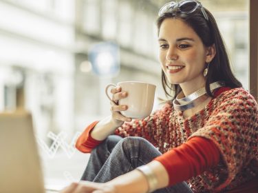 Eine junge Frau sitzt am Fenster und verändert ihre Gmail-Oberfläche