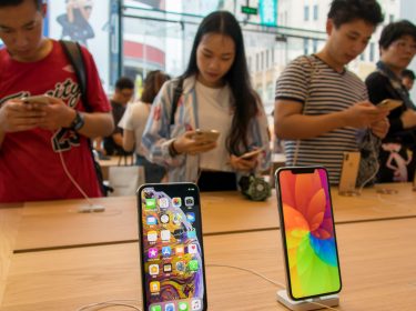 Kunden im Apple Store Shanghai hinter iPhone XS und XS Max