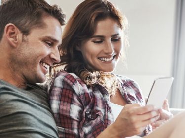 Junges Paar testet die neuen Gmail-Benachrichtigungen am Smartphone.