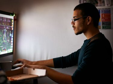 Junger Mann zockt ein PC-Spiel am Computer.