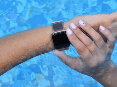Eine Apple Watch am Arm einer Person, über der Wasseroberfläche eines Pools