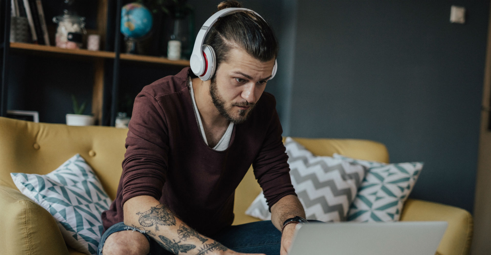 Junger Mann prüft die Audioeinstellungen seines Laptops.