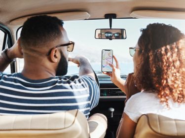 Paar nutzt im Auto eine Karten-App zur Navigation.