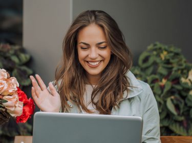 Junge Frau nutzt die Webcam für Videotelefonie mit dem Laptop.