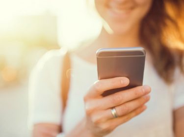 Junge Frau kontrolliert die Tiefenschärfe ihrer Smartphone-Bilder.