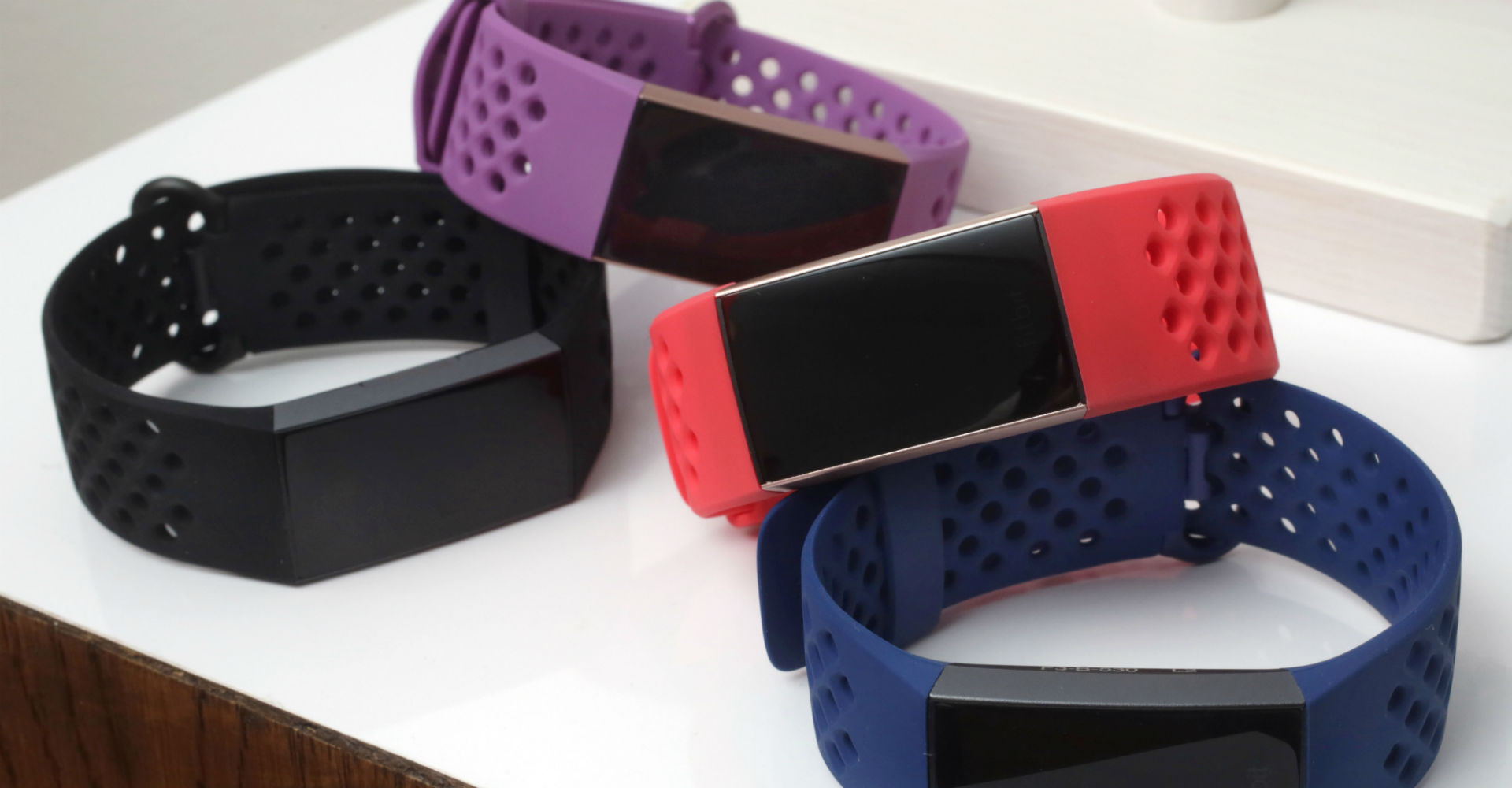 Mehrere Fitbit Charge 3 liegen gestapelt auf einem Tisch.