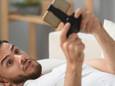 Junger Mann spielt Creative Destruction auf seinem Smartphone